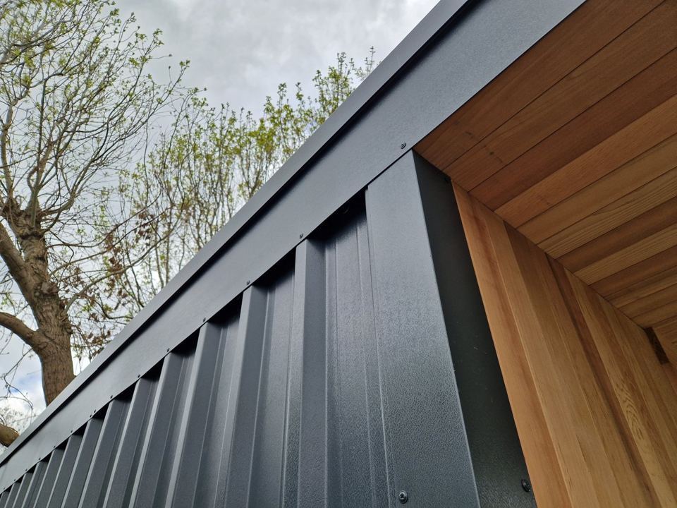Near-black box-profile steel against cedar